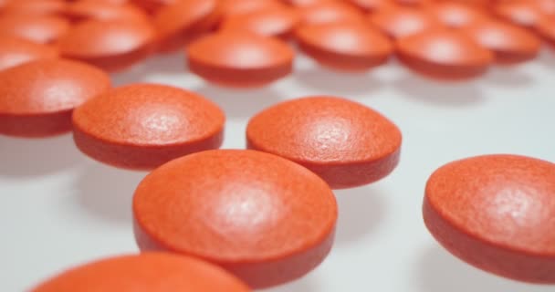 Medische achtergrond. gedetailleerde close-up van rode ronde pillen op wit oppervlak — Stockvideo