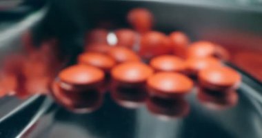 Detaylı, aşırı yakın çekim. Bir sürü kırmızı hap tıbbi tepsiye dökülüyor.