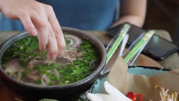 Close-up . female hands squeeze lime into a plate of pho bo soup — Stock Video