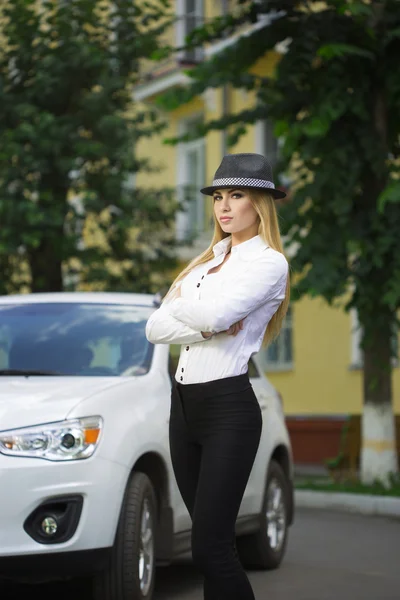 Fille dans un chapeau sur un fond de voiture blanche — Photo