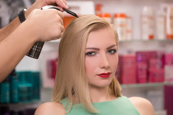 hairstylist makes hairstyle for beautiful girl