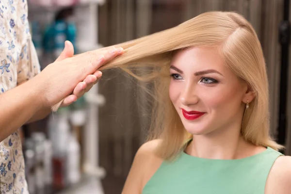 hairstylist makes hairstyle for beautiful girl