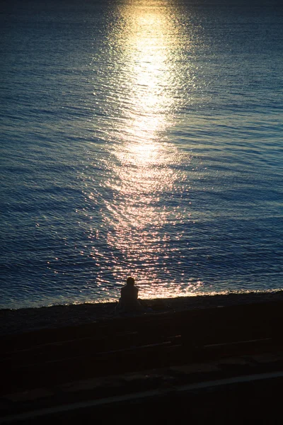 Silhouette assise jeune femme au coucher du soleil — Photo