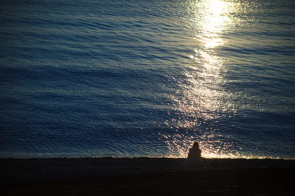 Sylwetka siedzi młoda kobieta na zachód słońca — Zdjęcie stockowe
