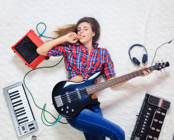 Девушка лежит на полу с бас-гитарой — стоковое фото