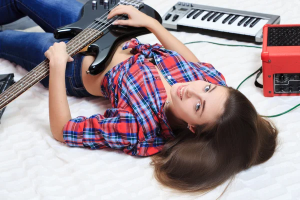 女孩躺在地上用低音吉他 — 图库照片