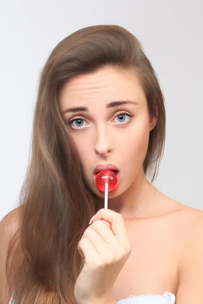 Menina com belo cabelo chupa um pirulito . — Fotografia de Stock