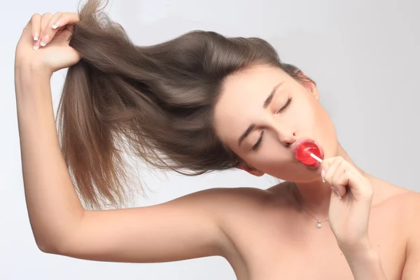 Girl with beautiful hair sucks a lollipop. — Stock Photo, Image