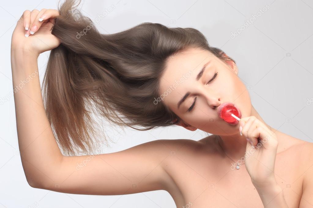 girl with beautiful hair sucks a lollipop.