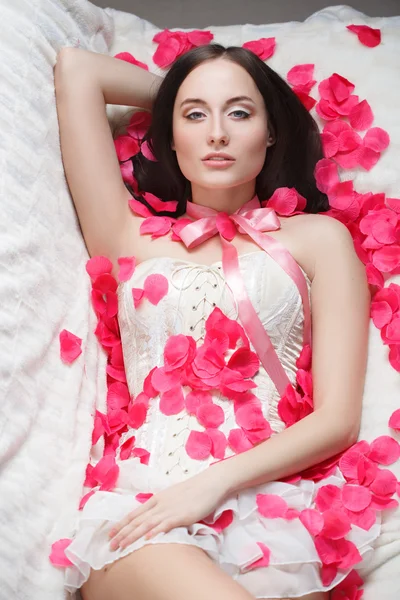 Gorgeous girl lying in rose petals. — Stock Photo, Image