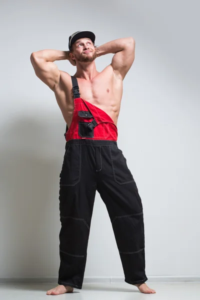 Muscular construction worker in overalls — Stock Photo, Image