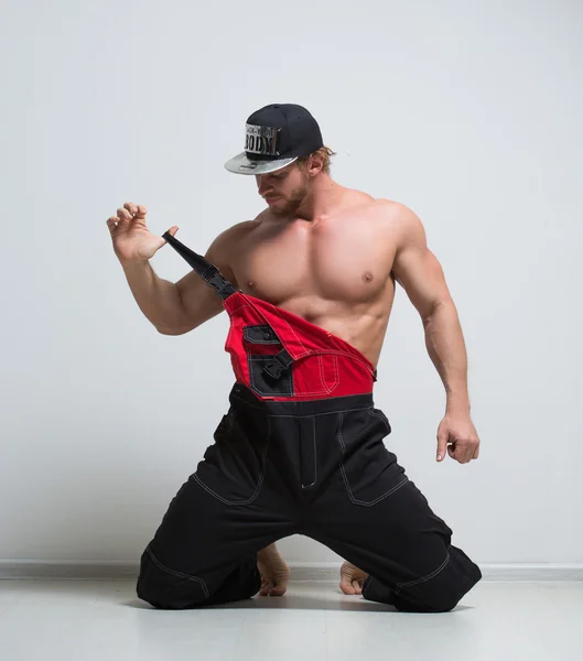 Muscular construction worker in overalls. kneeling — Stock Photo, Image