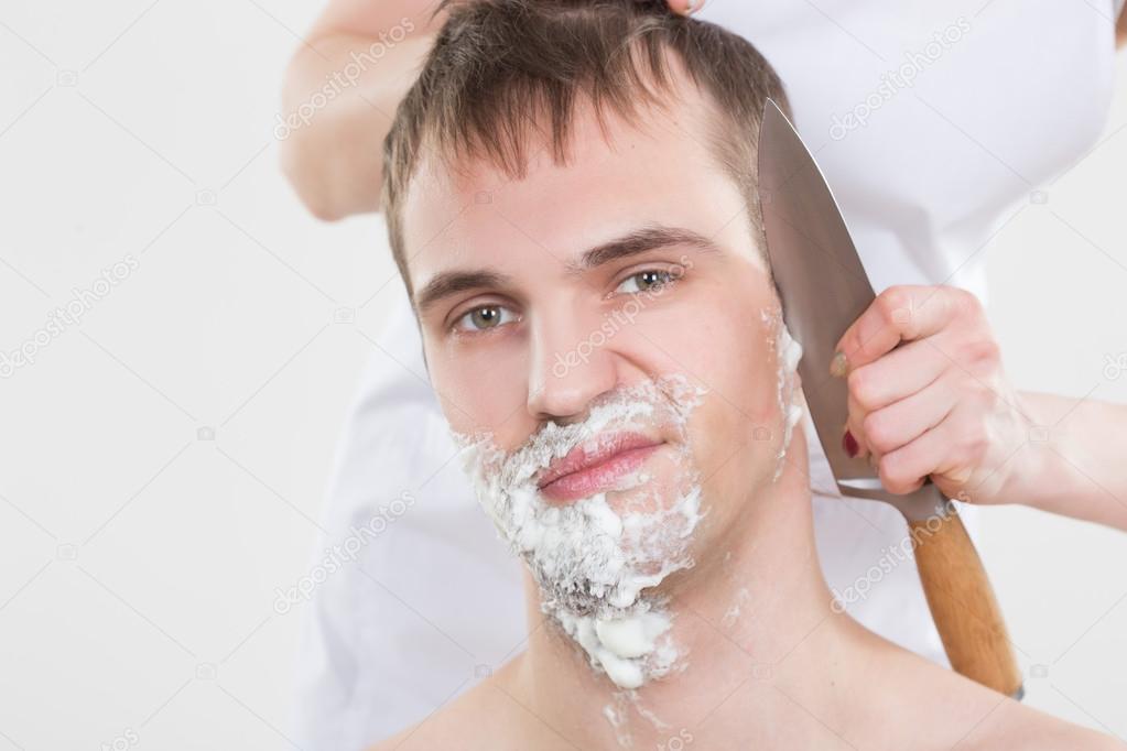 handsome man shaves a woman with a knife