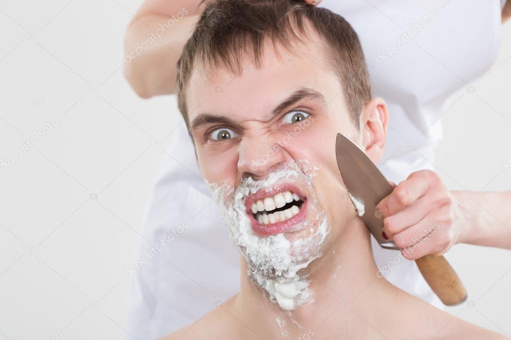 handsome man shaves a woman with a knife