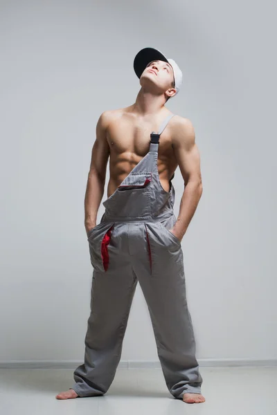 Muscular construction worker in overalls — Stock Photo, Image