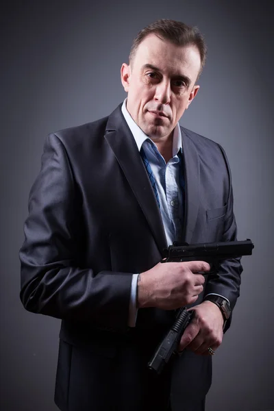 Man in a business suit with a gun — Stock Photo, Image