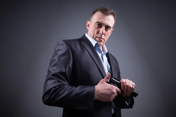 Man in a business suit with a gun — Stock Photo, Image