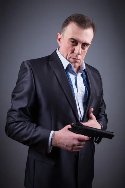 Man in a business suit with a gun — Stock Photo, Image