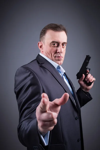 Man in a business suit with a gun — Stock Photo, Image