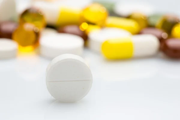 Pilha de várias pílulas coloridas isoladas em branco — Fotografia de Stock