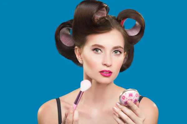 Female in curlers applying rouge. makeup brush. — Stock Photo, Image