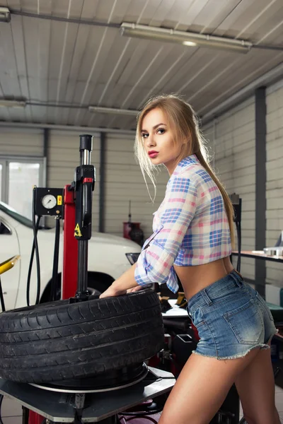 Dívka mechanik nahradit pneumatiky na kolečkách — Stock fotografie