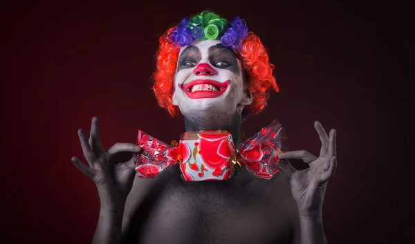 Scary clown with spooky makeup and more candy — Stock Photo, Image