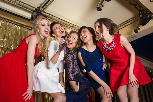 Happy girls singing into a microphone — Stock Photo, Image