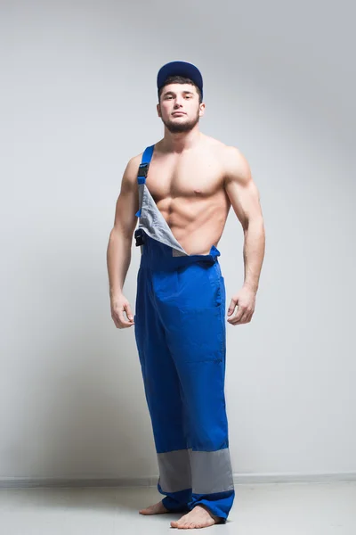 Muscular construction worker in overalls — Stock Photo, Image