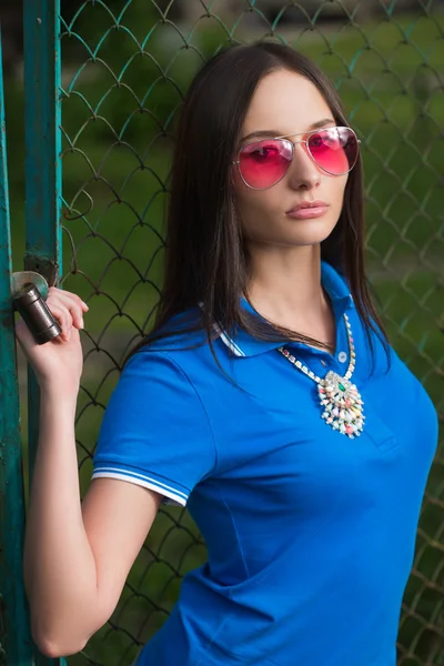 Young woman posing outdoor over fence mesh — Stock Photo, Image