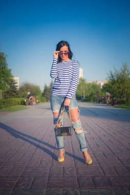 güzel esmer kız şehir sokaklarında yürüyor. yırtık kot pantolon ve ROP