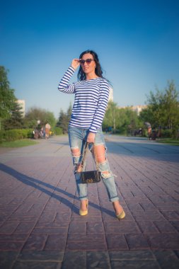 güzel esmer kız şehir sokaklarında yürüyor. yırtık kot pantolon ve ROP