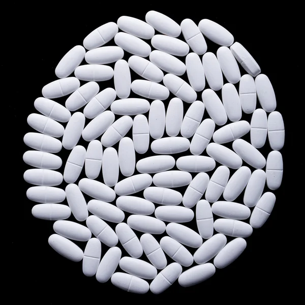 Bílé pilulky na černém — Stock fotografie