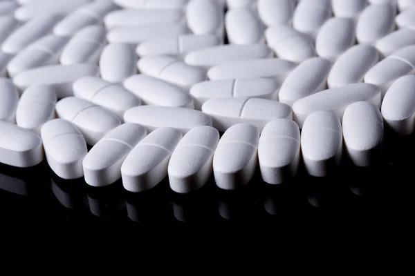 White pills on the black — Stock Photo, Image