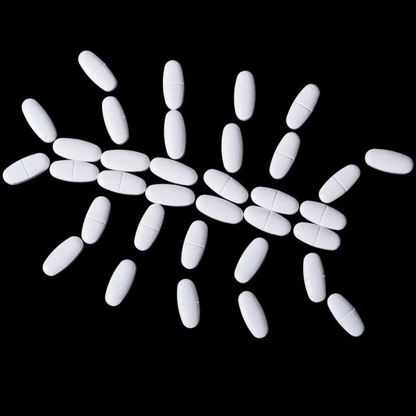 White pills on the black — Stock Photo, Image