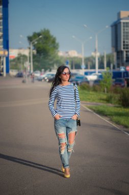 güzel esmer kız şehir sokaklarında yürüyor. yırtık kot pantolon ve ROP