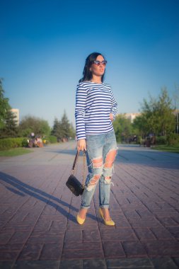 güzel esmer kız şehir sokaklarında yürüyor. yırtık kot pantolon ve ROP