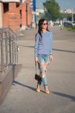 güzel esmer kız şehir sokaklarında yürüyor. yırtık kot pantolon ve ROP