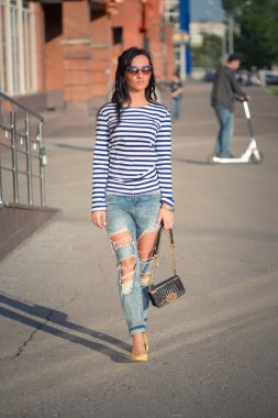 güzel esmer kız şehir sokaklarında yürüyor. yırtık kot pantolon ve ROP