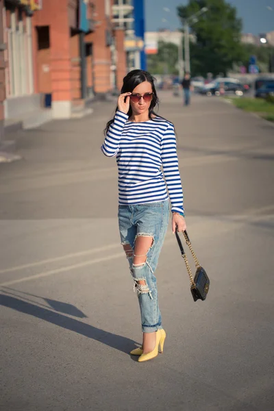 Beautiful brunette girl walks through the city streets. in torn jeans and frock — Stock Photo, Image