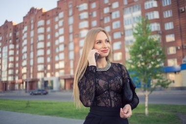 İş kadını sokakta cep telefonuyla konuşuyor.