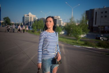 güzel esmer kız şehir sokaklarında yürüyor. yırtık kot pantolon ve ROP