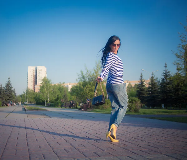 Beautiful brunette girl walks through the city streets. in torn jeans and frock — Stock Photo, Image
