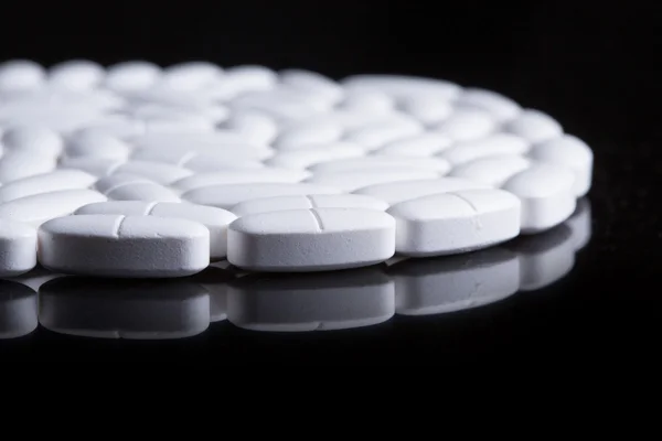 White pills on the black — Stock Photo, Image