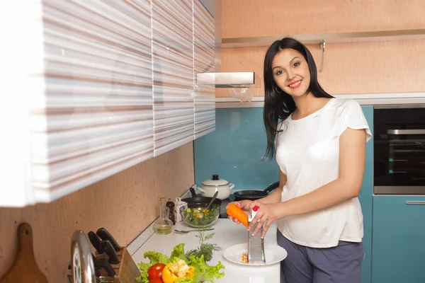 Senyum wanita muda di dapur dengan sayuran — Stok Foto