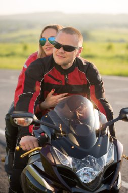 Motorcu adam ve bir motosiklet üzerinde oturan kadın.