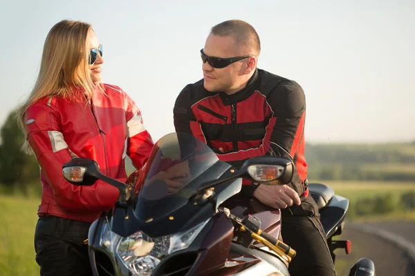 骑自行车的人男人和女人坐在一辆摩托车. — 图库照片
