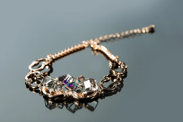 Golden bracelet with precious stones on grey background — Stock Photo, Image