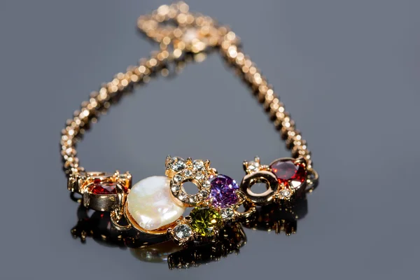 Golden bracelet with precious stones on grey background — Stock Photo, Image