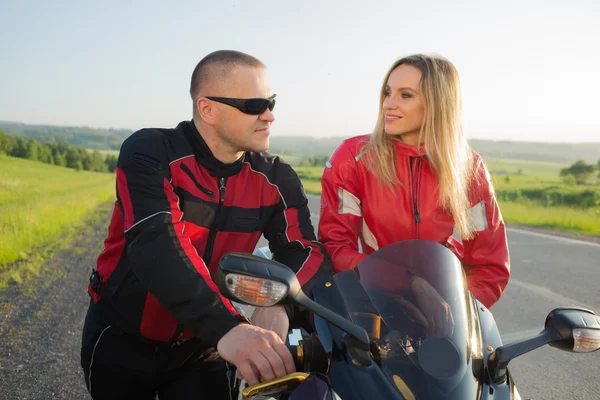 biker man and woman sitting on a motorcycle.